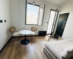 A room with a bed, two chairs, a small table, a window, and a door. - Aix-en-Provence, Air-Conditioned Apartment with a Terrace (Aix-en-Provence)