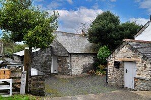 A stone building with a white door and a small porch area. - Cottage Near Beaches Cornwall (Wadebridge)