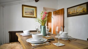 A dining table set with white plates, bowls, and cutlery, accompanied by a vase of flowers and a green pitcher. - Scenic Snowdonia Border Cottage for 4 (Caernarfon)