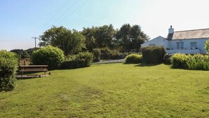 A grassy outdoor area with a picnic table and a white building with a sloped roof. - Scenic Snowdonia Border Cottage for 4 (Caernarfon)