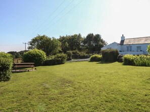 A grassy outdoor area with a picnic table and a white building with a sloped roof.