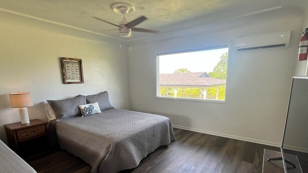 A bedroom with a bed, a nightstand, a window, and a ceiling fan.