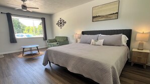 Ein Schlafzimmer mit einem großen Bett, einem Sessel, einem kleinen Tisch und einem Deckenventilator.