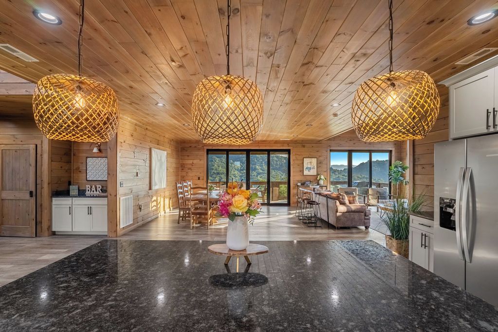 A modern kitchen with granite countertops, wooden ceiling, and pendant lighting.