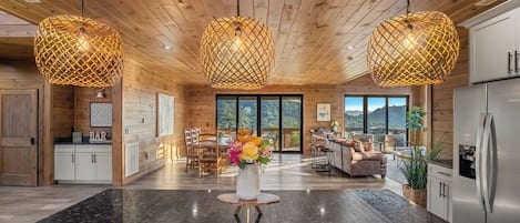 A modern kitchen with granite countertops, wooden ceiling, and pendant lighting.