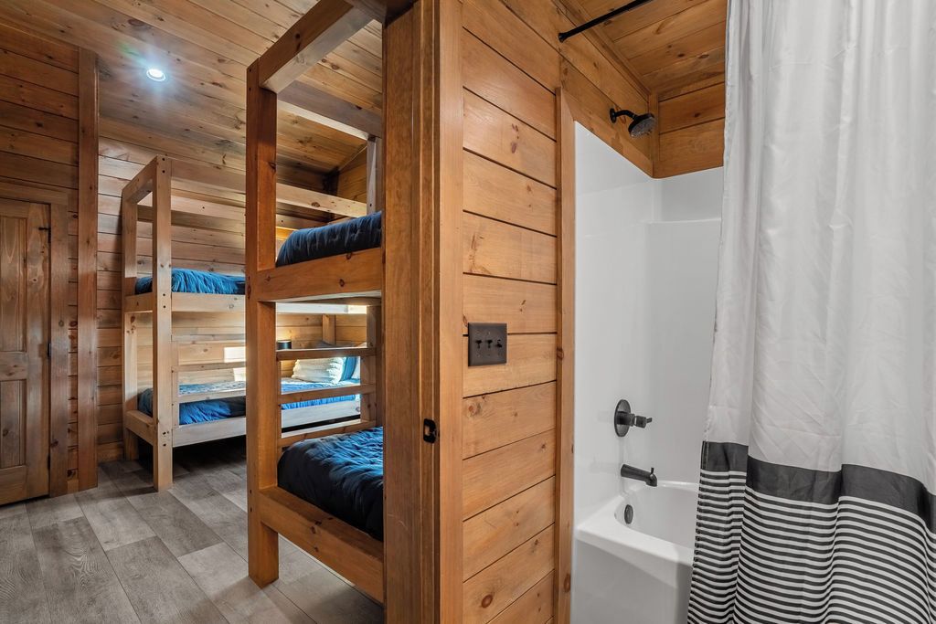 A wooden interior with bunk beds, a bathtub, and a shower curtain.