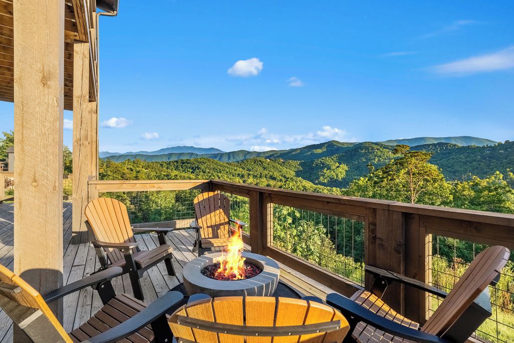 A deck with a fire pit, seating, and a view of mountains.