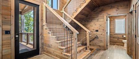 A wooden interior with a staircase, a door, and a window.