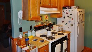 A kitchen with wooden cabinets, a stove, a refrigerator, and a phone on the wall. - Nature Lover’s Retreat: Cozy 2-Bedroom Pine Mountain Cabin near Callaway Gardens (Pine Mountain)