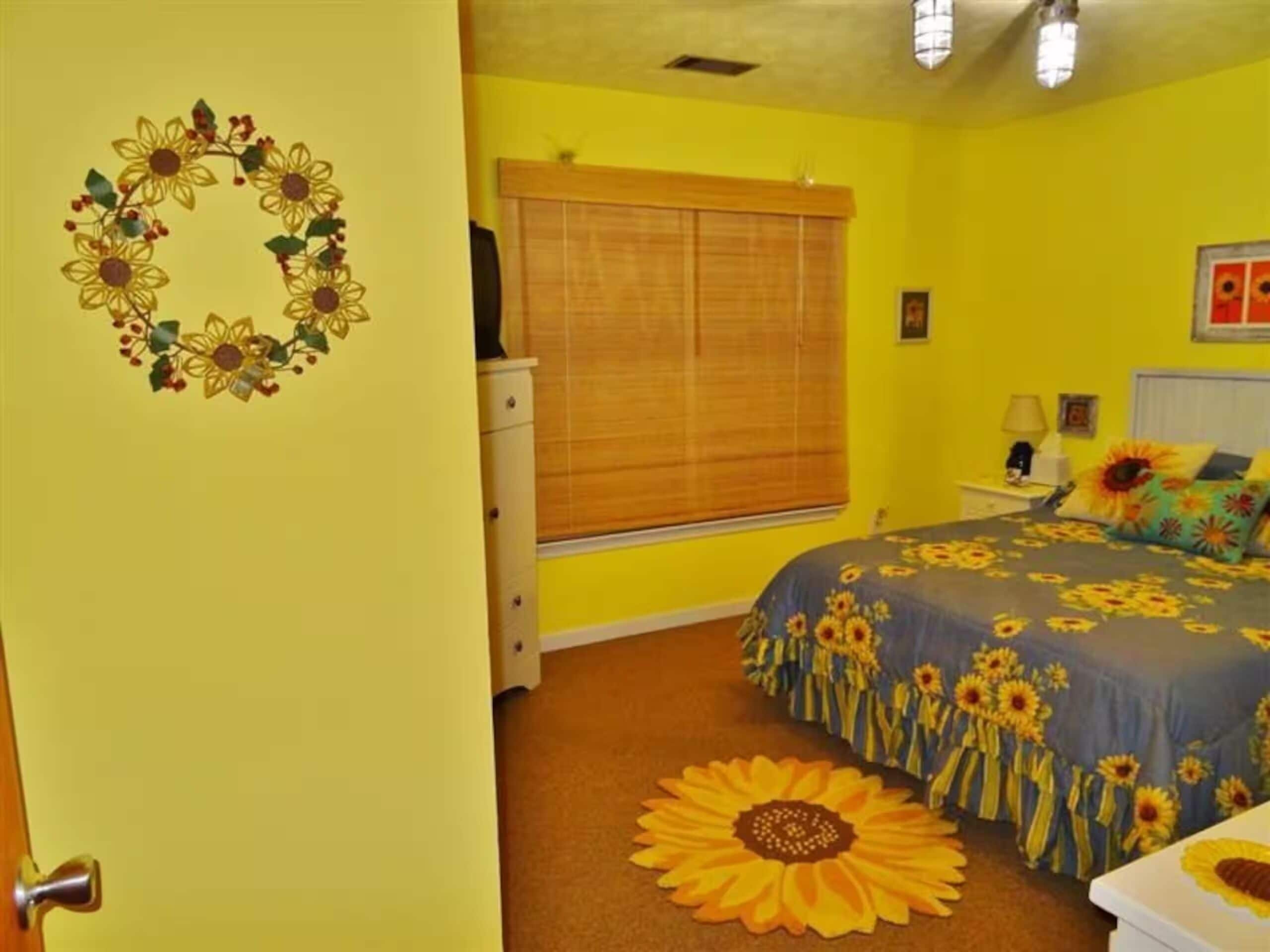 A bedroom with a bed, a dresser, a window with blinds, and a wall decoration.