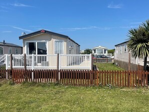 A mobile home with a deck and a fenced yard.