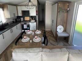 A modern kitchen with white cabinets, a dining table set for four, and a wooden bench.