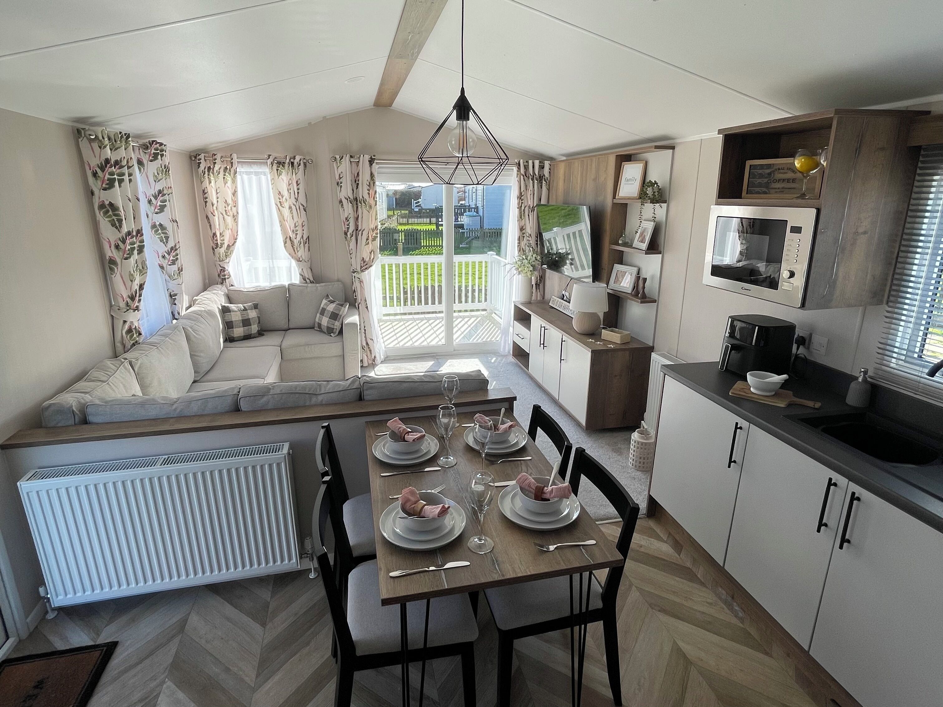 Un espacio de sala acogedor con sofá, mesa de comedor para dos personas y cocina con electrodomésticos modernos.