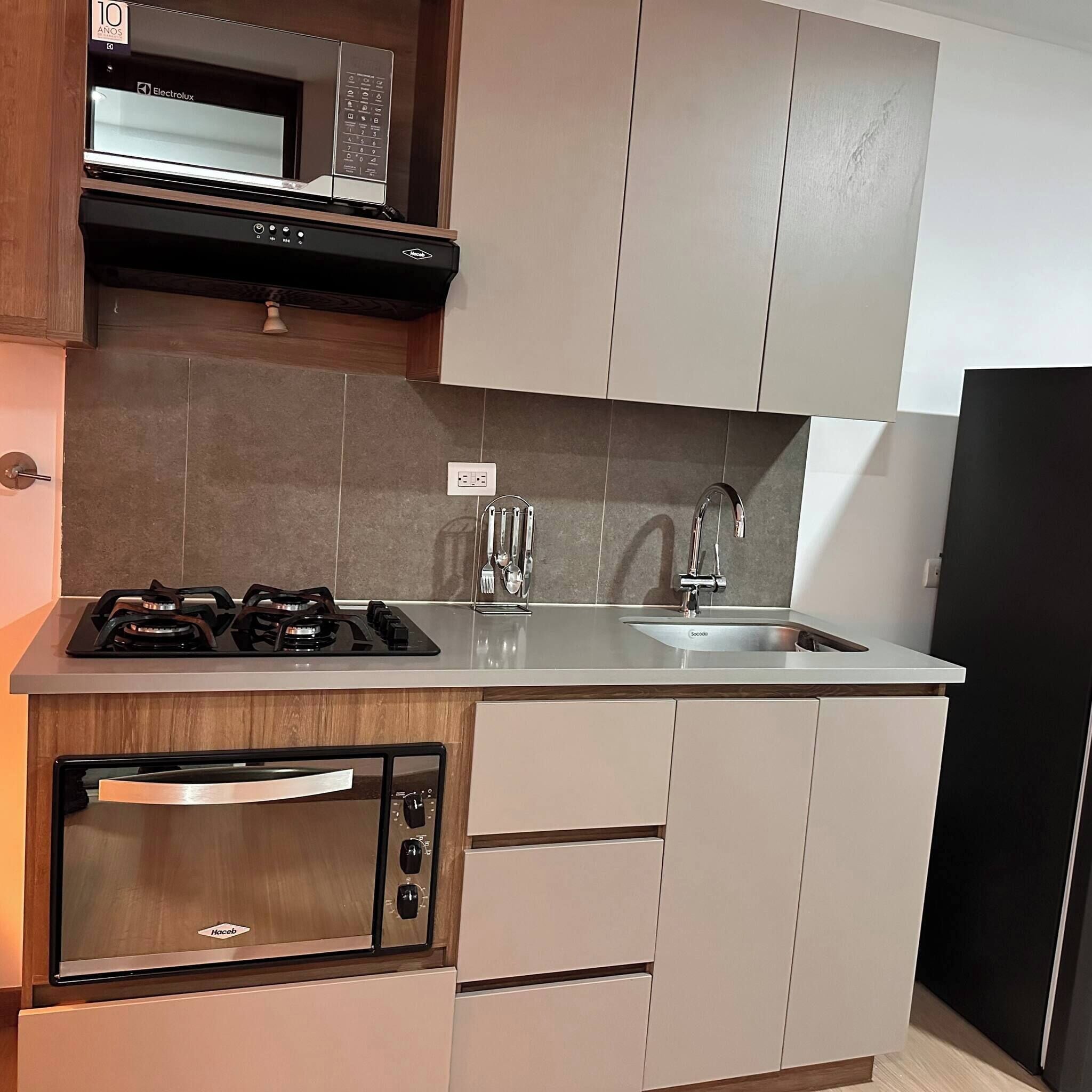 A modern kitchen with a microwave, stove, oven, and sink.