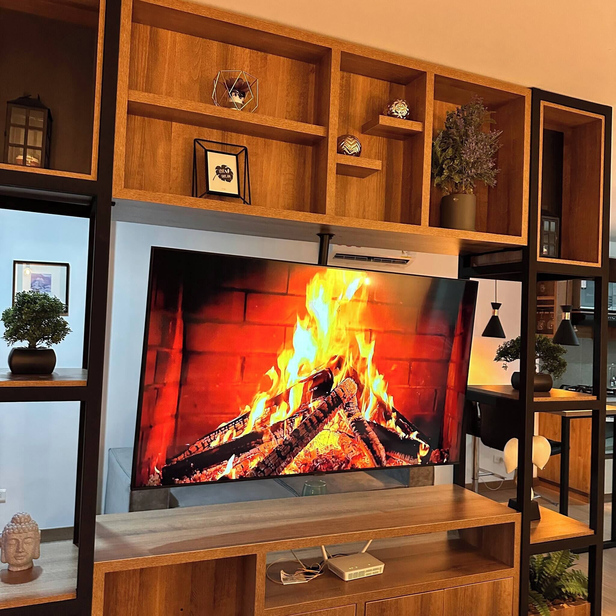 A modern living room with a fireplace, wooden shelving, and decorative items.