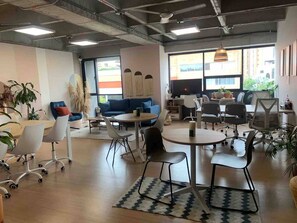 A modern office space with a blue sofa, round tables, and white chairs. - Premium Loft With AC Panoramic View in Laureles (Medellín)