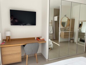A modern bedroom with a wooden desk, a grey chair, a bed with white bedding, a television, and a mirrored wardrobe. - Exceptional new contemporary villa with air conditioning, ocean views, a private pool, and a hot tub (Saint-Cyr-sur-Mer)