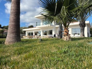 A modern house with a patio area, outdoor furniture, and a palm tree. - Exceptional new contemporary villa with air conditioning, ocean views, a private pool, and a hot tub (Saint-Cyr-sur-Mer)