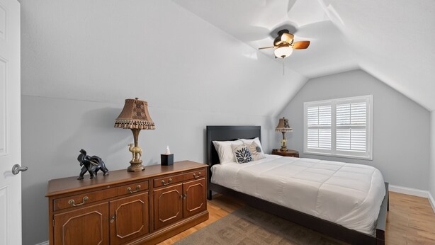 A bedroom with a bed, a wooden dresser, a ceiling fan, and a window with blinds. - Black Walnut - 4 Blocks to Kirkwood / Downtown w/ at home Gym (Bloomington)