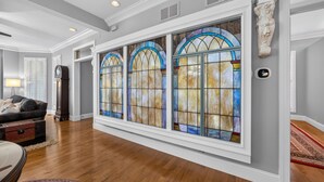 A spacious hallway with wooden flooring, a large stained glass window, and a classical statue. - Black Walnut - 4 Blocks to Kirkwood / Downtown w/ at home Gym (Bloomington)