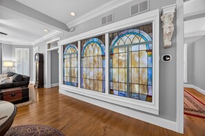 A spacious hallway with wooden flooring, a large stained glass window, and a classical statue. - Black Walnut - 4 Blocks to Kirkwood / Downtown w/ at home Gym (Bloomington)