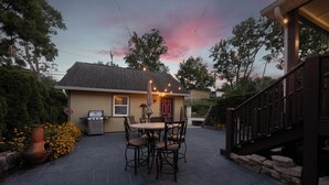 A patio with a table and chairs, a grill, and a house with a red door. - Black Walnut - 4 Blocks to Kirkwood / Downtown w/ at home Gym (Bloomington)