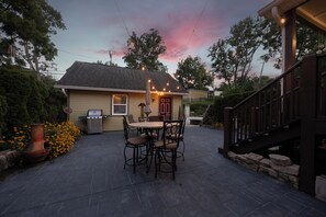 A patio with a table and chairs, a grill, and a house with a red door. - Black Walnut - 4 Blocks to Kirkwood / Downtown w/ at home Gym (Bloomington)