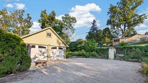A residential property with a garage, a gravel driveway, and a stone wall. - Black Walnut - 4 Blocks to Kirkwood / Downtown w/ at home Gym (Bloomington)
