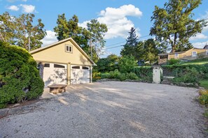 A residential property with a garage, a gravel driveway, and a stone wall. - Black Walnut - 4 Blocks to Kirkwood / Downtown w/ at home Gym (Bloomington)
