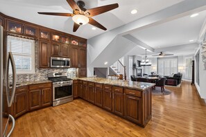 A modern kitchen with wooden cabinets, stainless steel appliances, and a large island. - 4 Blocks to IU! 3BR Stay w/ Parking, Gym & FirePit (Bloomington)