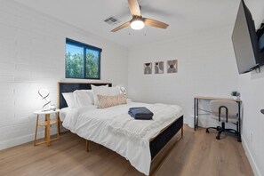 A bedroom with a bed, a desk, a chair, a ceiling fan, and a window. - Biltmore 2BR Bungalow - Desk, Parking, Patio (Phoenix)