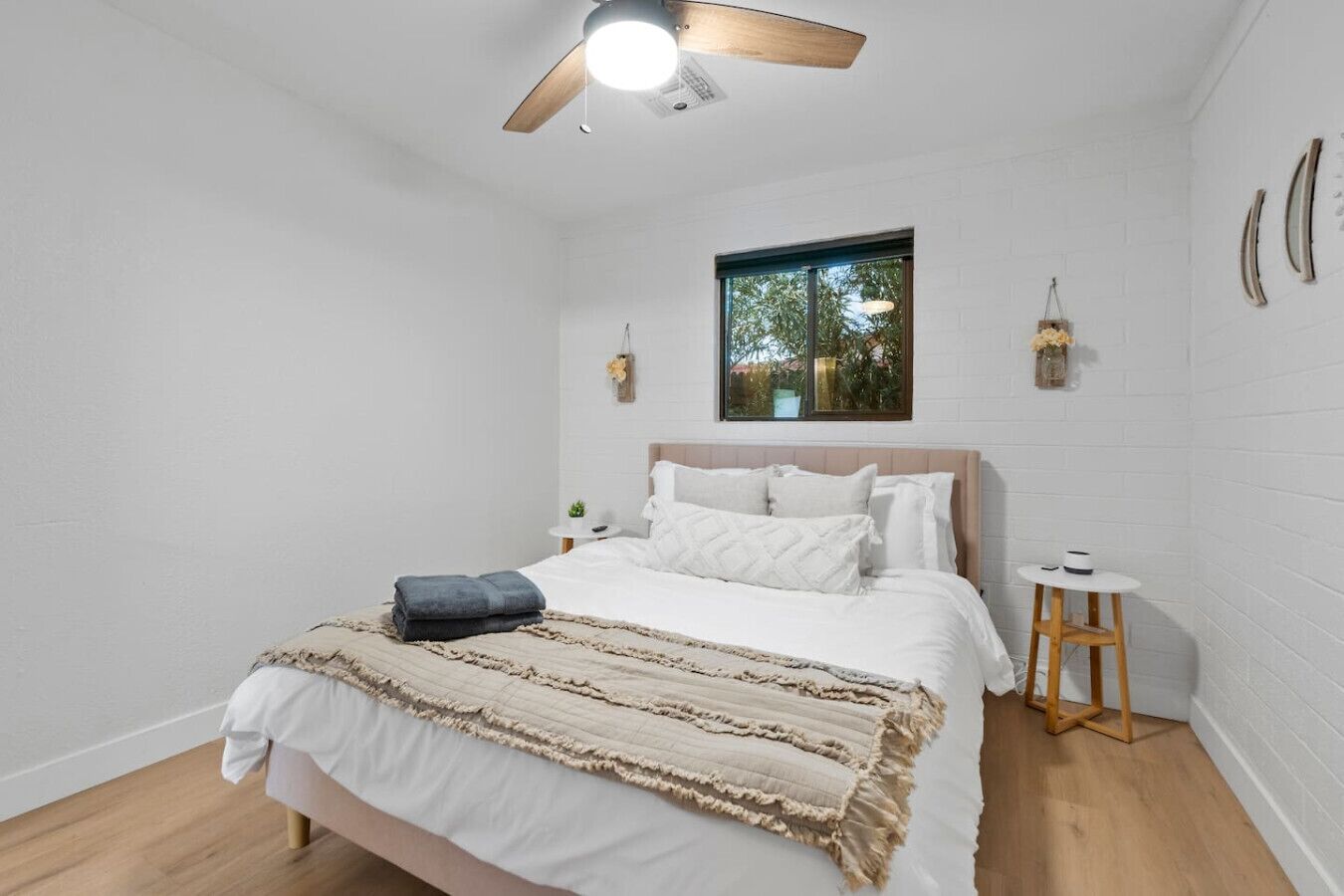 A bedroom with a bed, a bedside table, a window, and a ceiling fan.