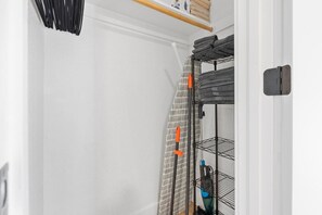 Un placard blanc avec une étagère en métal contenant des serviettes pliées et une bouteille bleue.