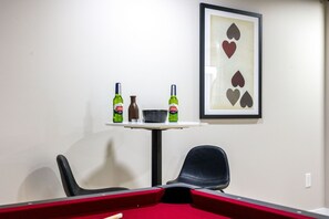 A pool table with two bottles of Stella Artois beer, a small bowl, and a framed playing card on the wall. - Theater · HotTub · PoolTable · Walk ND · Sleeps 12 (South Bend)