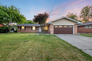 A single-story house with a garage, a well-maintained lawn, and a tree in the front yard. - Theater · HotTub · PoolTable · Walk ND · Sleeps 12 (South Bend)
