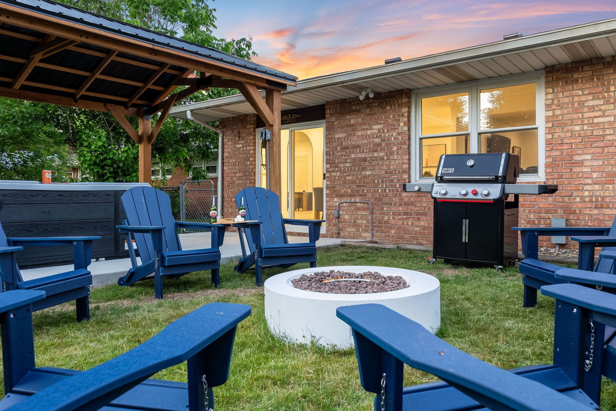 An outdoor seating area with Adirondack chairs, a fire pit, and a barbecue grill.
