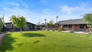 A residential property with a well-maintained lawn, a brick house, and a fenced yard. - Biltmore 2BR Bungalow - Desk, Parking, Patio (Phoenix)