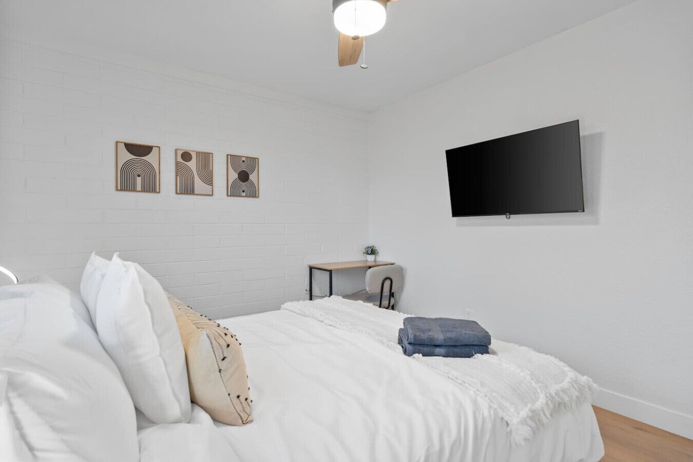Une chambre à coucher avec un lit, un bureau et un téléviseur fixé au mur.
