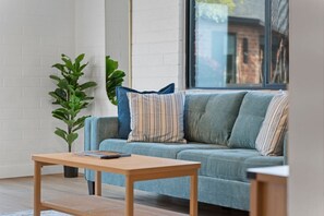 A modern living room with a sofa, a coffee table, and a potted plant. - Biltmore 2BR Bungalow - Desk, Parking, Patio (Phoenix)