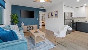 A modern living room with a sofa, coffee table, and a TV mounted on the wall. - Biltmore 2BR Bungalow - Desk, Parking, Patio (Phoenix)