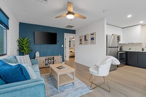 Uma sala de estar moderna com um sofá, mesa de centro e televisão fixada na parede.