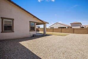 A residential area with houses, a covered patio, and a gravel driveway. - Bright & Modern Home w/ Open Living, Great Area, & Perfect for Families! (Sun City West)
