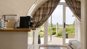 Una cocina moderna con cafetera integrada, encimera de madera y vistas a un espacio exterior por medio de un ventanal.