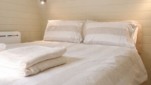 Un dormitorio con una cama individual, ropa de cama blanca y una lámpara en el techo.