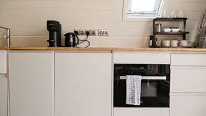 A kitchen with a built-in oven, a coffee maker, and a window above the countertop. - Croft 21 Glamping (Beauly)