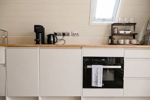 Una cocina con horno empotrado, cafetera y ventana sobre la encimera.