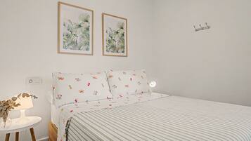 A bedroom with a bed, a bedside table with a lamp, and two framed pictures on the wall.