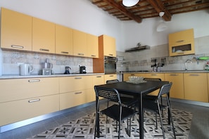 Una cocina con armarios amarillos, un comedor con mesa negra y un piso con diseño.