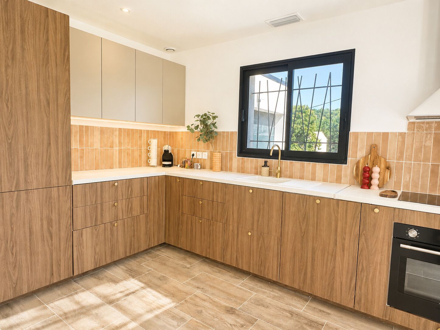 A modern kitchen with wooden cabinets, a built-in oven, and a window.