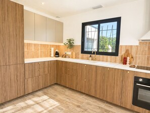 A modern kitchen with wooden cabinets, a built-in oven, and a window. - June House in the Heart of the Luberon—Ducted Air Conditioning, All the Comforts, and a Private Garden (Saignon)